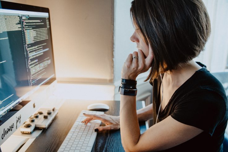 mulher olha para o computador com atenção